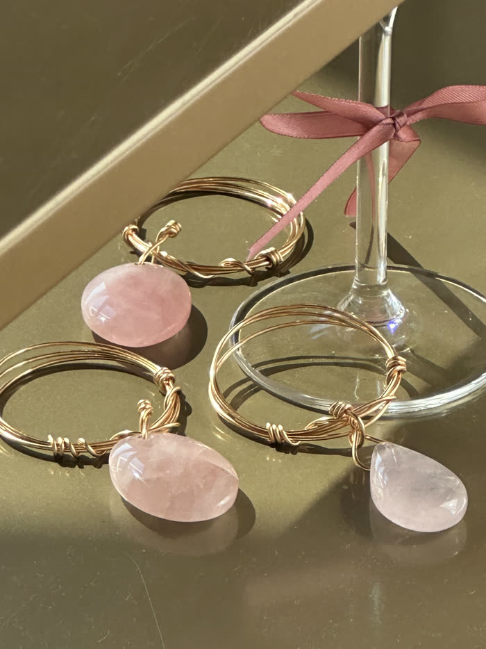 Gold napkin rings with rose quartz on an olive surface, tied with a ribbon