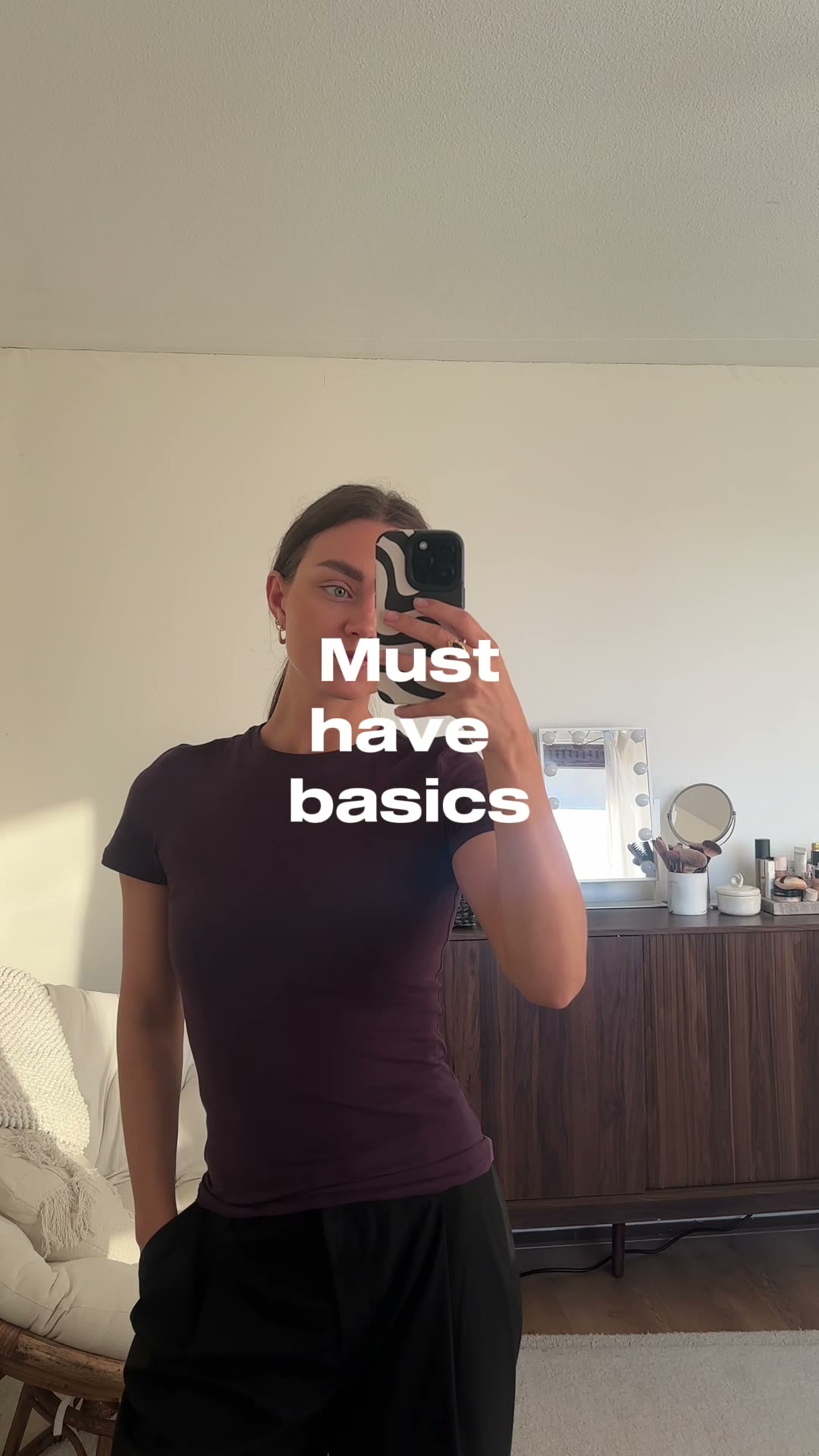 Sabine wearing a brown basic shirt in front of a mirror