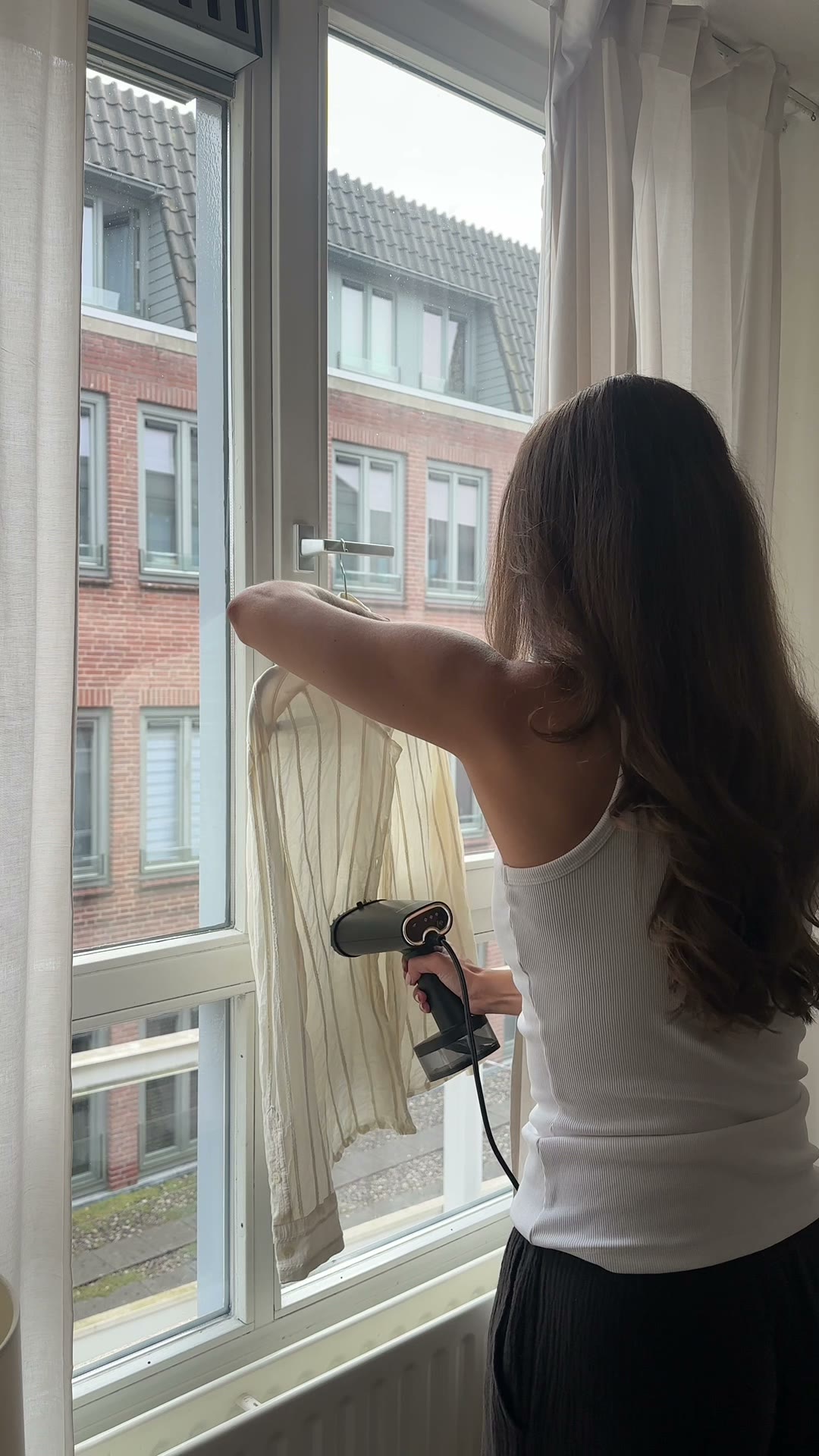 Sabine by the window with a garment steamer